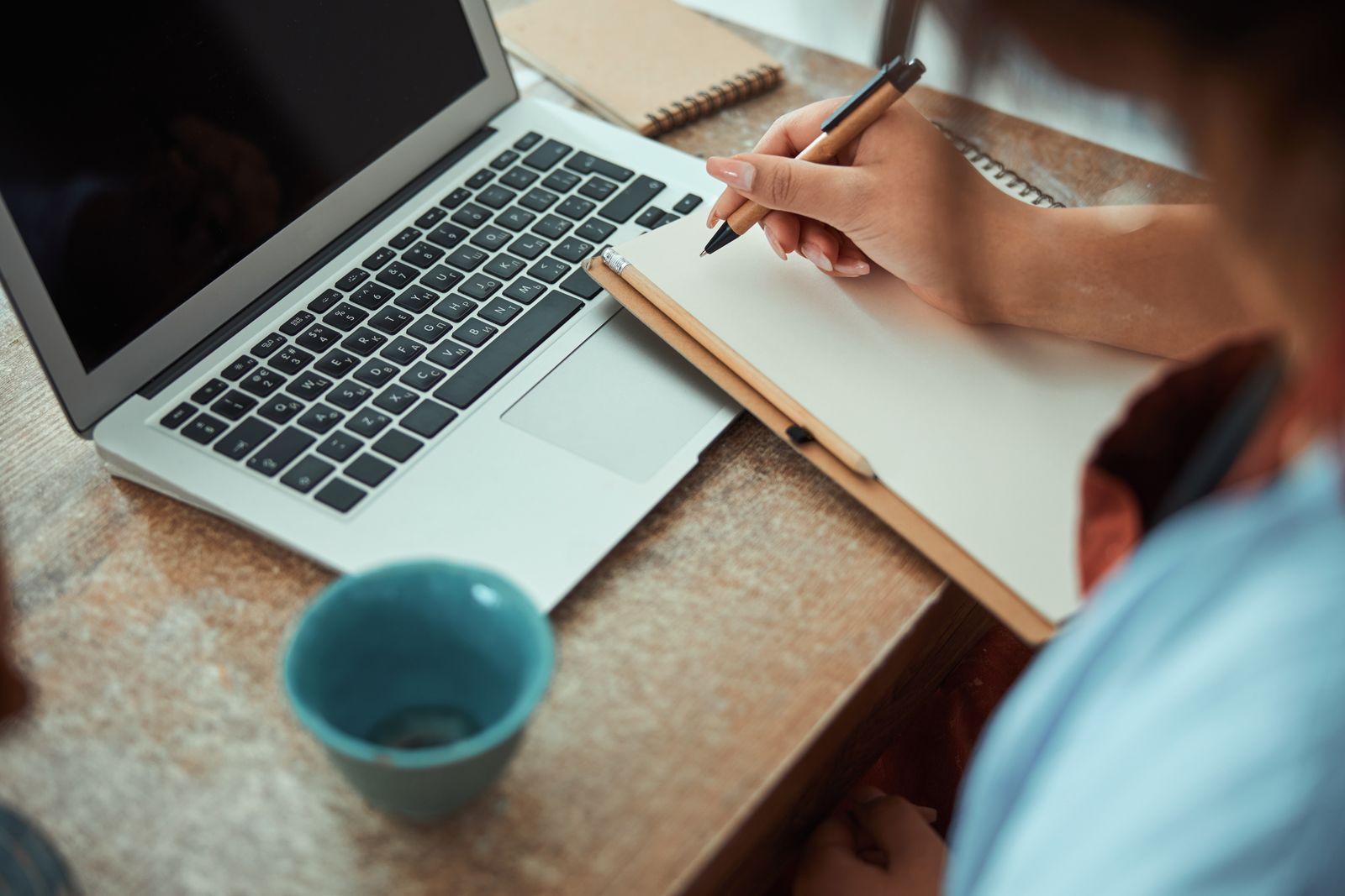 Un carnet de notes, un ordinateur portable et une tasse sur un bureau